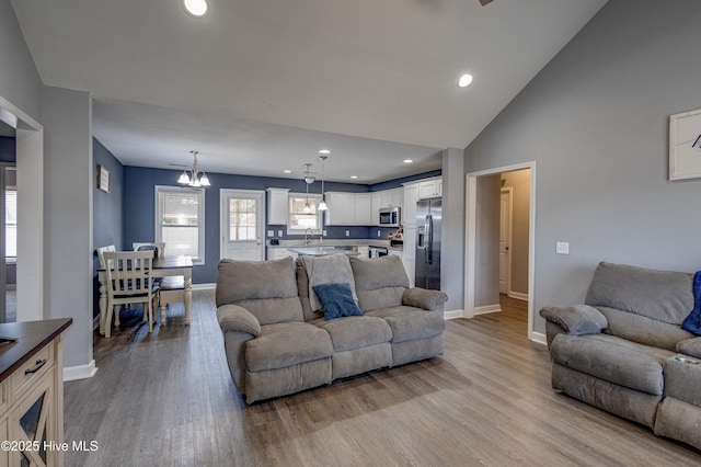 living area featuring a chandelier, recessed lighting, wood finished floors, and baseboards