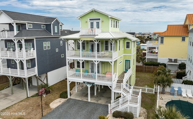 rear view of house with driveway, a porch, a balcony, french doors, and a carport