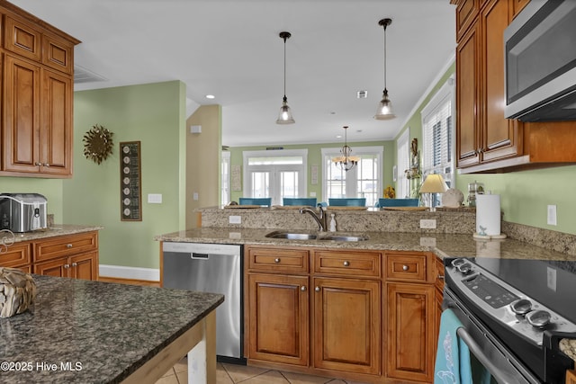 kitchen with a peninsula, brown cabinetry, appliances with stainless steel finishes, and a sink