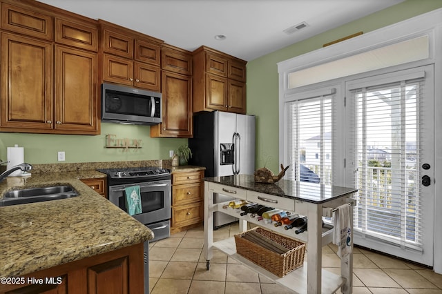 kitchen with light tile patterned floors, visible vents, a sink, stainless steel appliances, and brown cabinets