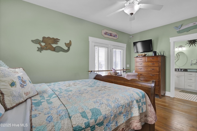 bedroom with connected bathroom, baseboards, wood finished floors, and a ceiling fan