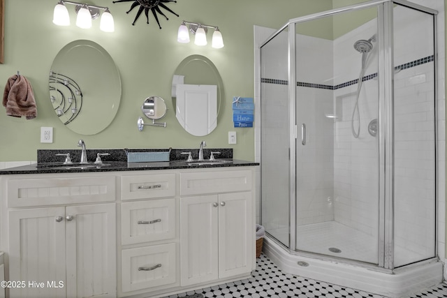 bathroom featuring a shower stall, double vanity, and a sink