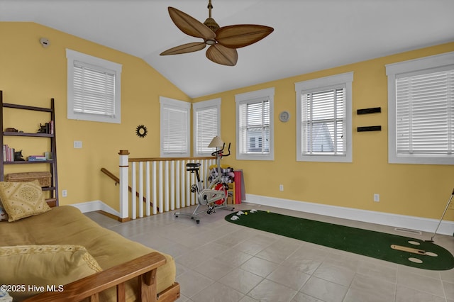 exercise room with vaulted ceiling, a ceiling fan, baseboards, and tile patterned floors