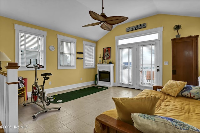 workout room featuring a ceiling fan, baseboards, lofted ceiling, a glass covered fireplace, and tile patterned floors