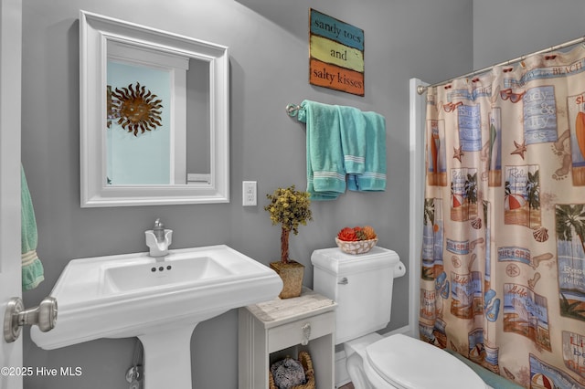 bathroom featuring a sink, a shower with curtain, and toilet