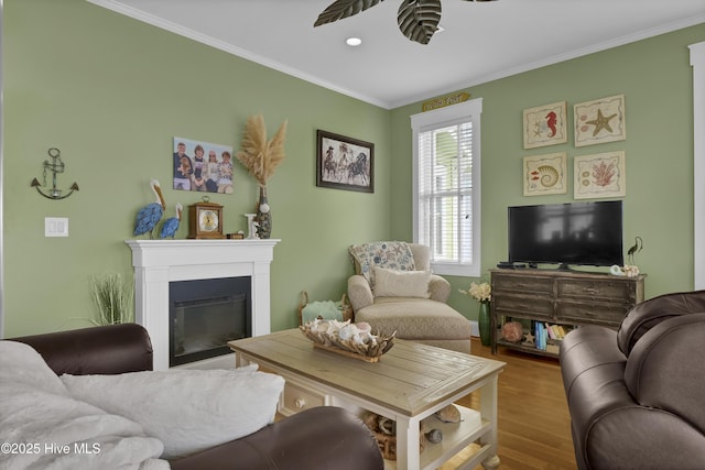 living room with wood finished floors, a ceiling fan, recessed lighting, a glass covered fireplace, and crown molding