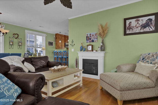 living area featuring a glass covered fireplace, crown molding, and wood finished floors