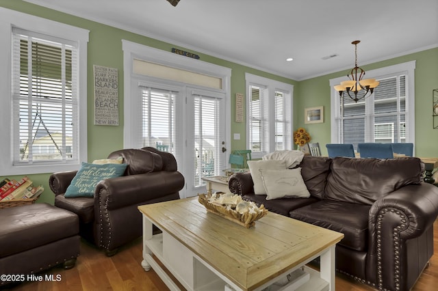 living room with an inviting chandelier, crown molding, wood finished floors, and visible vents