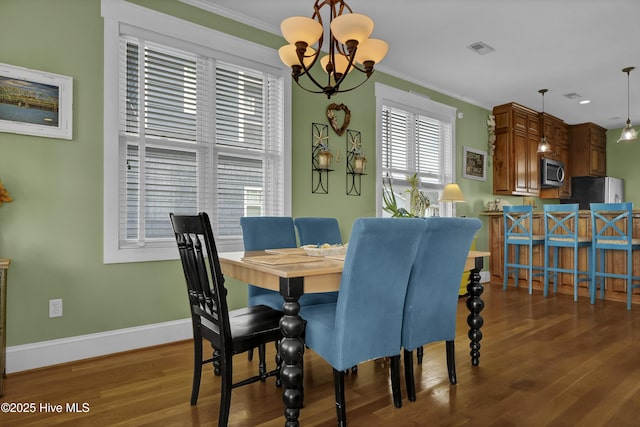 dining room with visible vents, crown molding, baseboards, an inviting chandelier, and wood finished floors