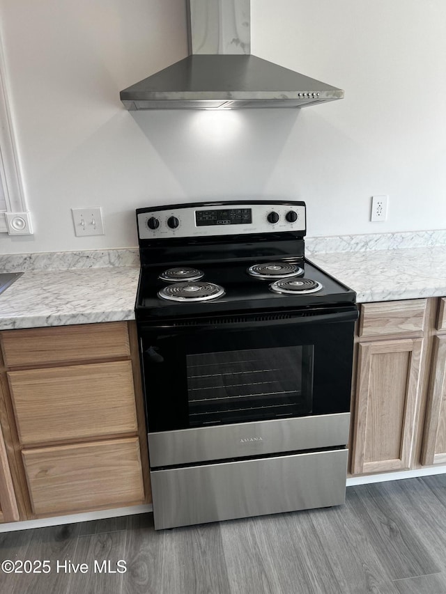 kitchen featuring stainless steel electric stove, light countertops, light brown cabinetry, wall chimney range hood, and wood finished floors