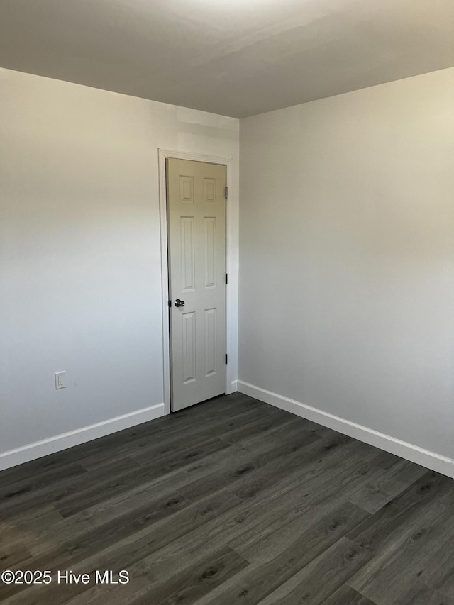 unfurnished room with dark wood-type flooring and baseboards