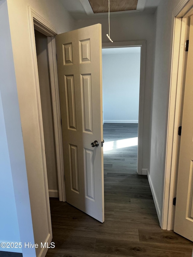 hallway featuring attic access, baseboards, and dark wood finished floors