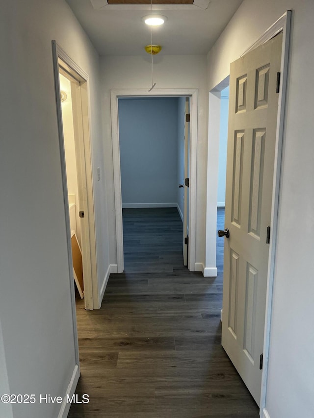 corridor with attic access, dark wood finished floors, and baseboards