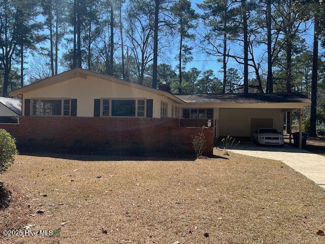 view of front of home with an attached carport, concrete driveway, and brick siding