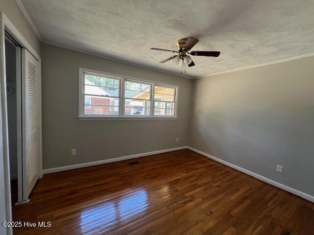 unfurnished bedroom featuring baseboards, a textured ceiling, ornamental molding, and wood finished floors