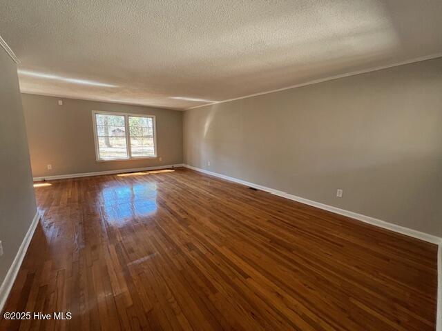 unfurnished room with dark wood-style floors, baseboards, and a textured ceiling