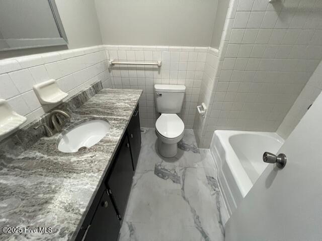 full bathroom with marble finish floor, wainscoting, vanity, and toilet