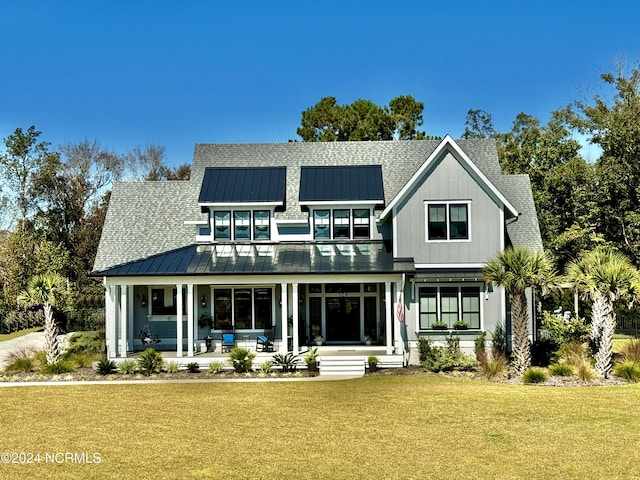 rear view of house with covered porch, a yard, a standing seam roof, and metal roof