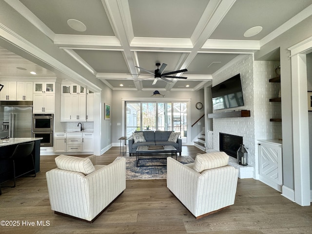 living area featuring dark wood-type flooring, coffered ceiling, a fireplace, baseboards, and beamed ceiling