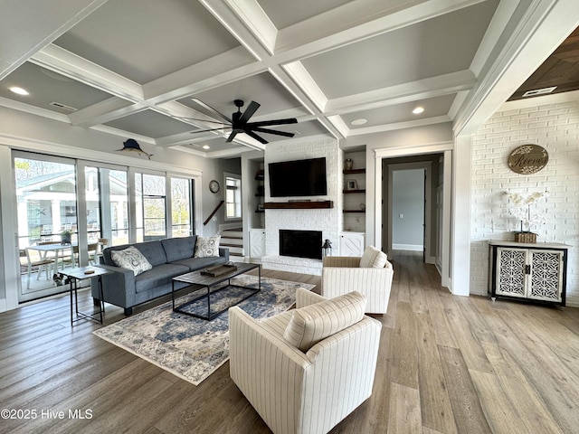 living room featuring a fireplace, visible vents, wood finished floors, coffered ceiling, and beamed ceiling