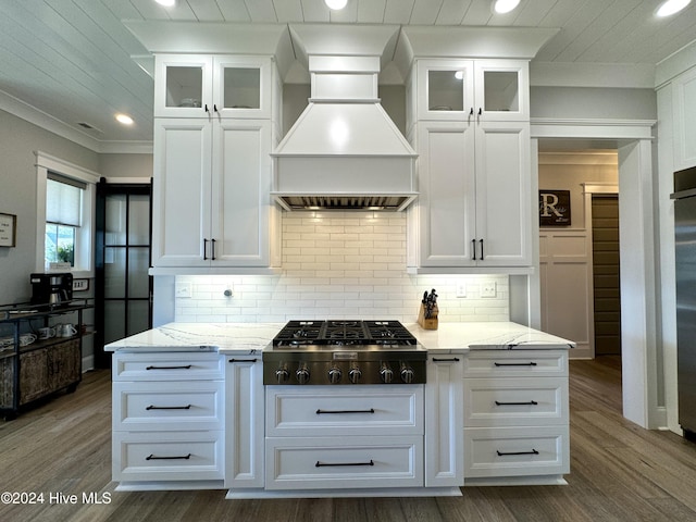 kitchen featuring stainless steel gas cooktop, premium range hood, white cabinetry, and tasteful backsplash