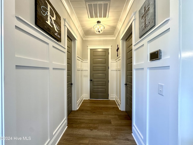 hall with crown molding, dark wood-type flooring, visible vents, and a decorative wall