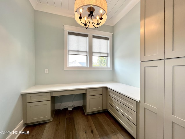 unfurnished office with built in desk, dark wood-type flooring, an inviting chandelier, and baseboards