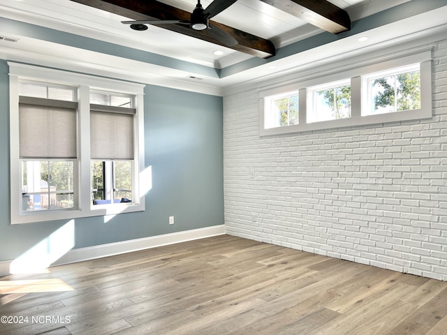 unfurnished room with brick wall, beamed ceiling, wood finished floors, and a healthy amount of sunlight