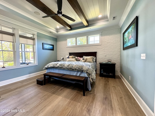 bedroom with baseboards, multiple windows, beam ceiling, and wood finished floors