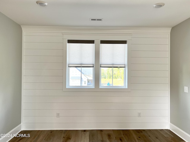 unfurnished room with dark wood-style floors, visible vents, and baseboards