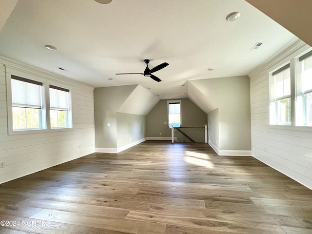 bonus room featuring lofted ceiling, visible vents, wood walls, and wood finished floors