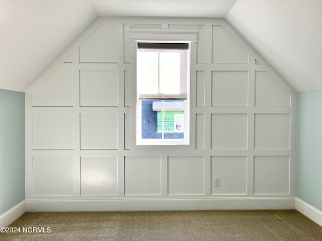 bonus room with lofted ceiling, baseboards, carpet flooring, and a decorative wall