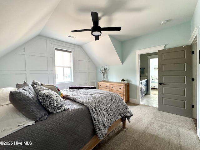 bedroom featuring lofted ceiling, visible vents, a decorative wall, and light carpet