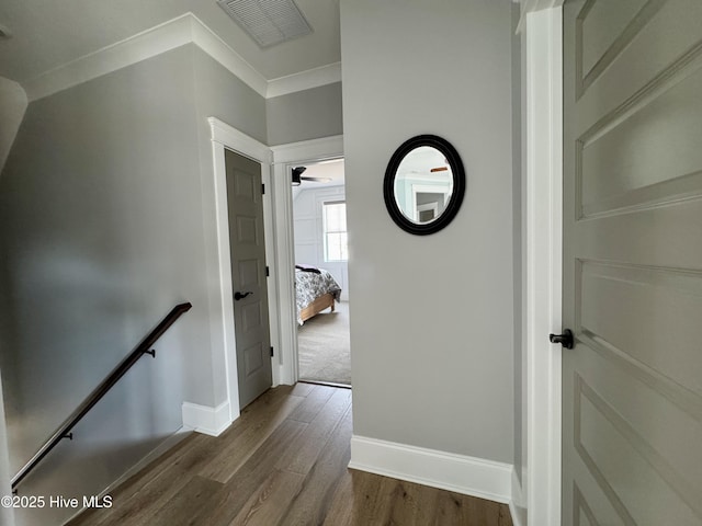 corridor featuring dark wood finished floors, an upstairs landing, visible vents, and baseboards