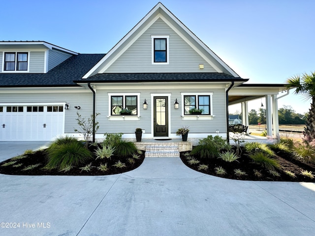 view of front of property with a garage, concrete driveway, and roof with shingles