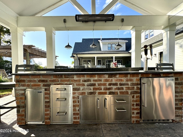 view of patio with outdoor wet bar, an outdoor kitchen, and a pergola