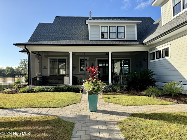 view of front of property featuring a front lawn, a shingled roof, fence, and a sunroom