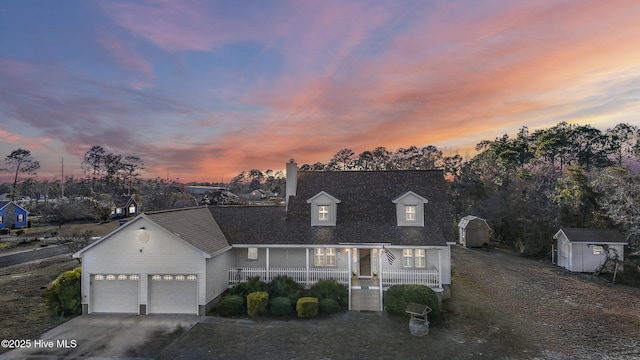 view of front of home with an outbuilding, a porch, an attached garage, a shed, and driveway