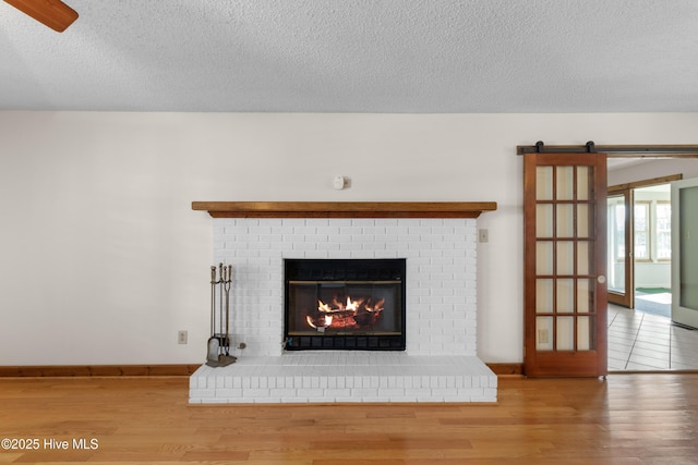 details featuring a fireplace, a barn door, a textured ceiling, wood finished floors, and baseboards