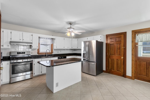 kitchen featuring white cabinets, a sink, stainless steel appliances, under cabinet range hood, and backsplash