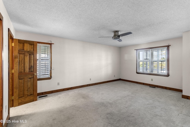 spare room with baseboards, visible vents, a ceiling fan, a textured ceiling, and carpet flooring