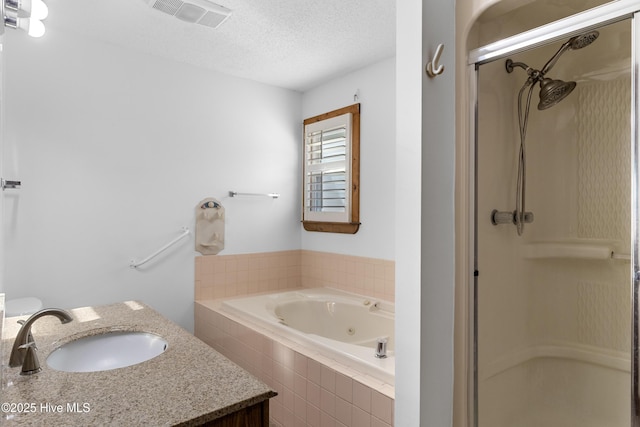 full bathroom featuring a stall shower, visible vents, a jetted tub, a textured ceiling, and vanity