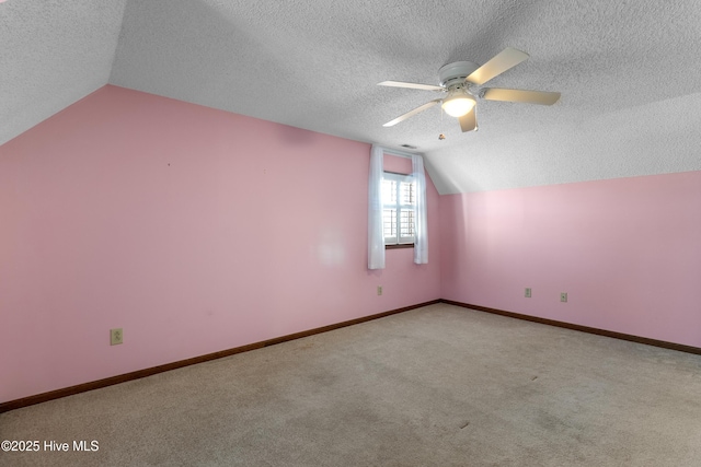 bonus room with carpet, lofted ceiling, ceiling fan, a textured ceiling, and baseboards