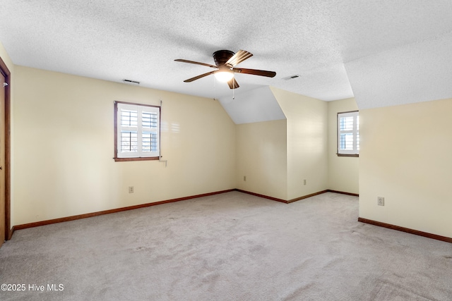 additional living space with ceiling fan, lofted ceiling, carpet flooring, visible vents, and baseboards