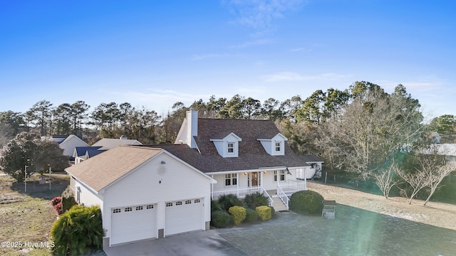 new england style home featuring an attached garage, a chimney, and concrete driveway