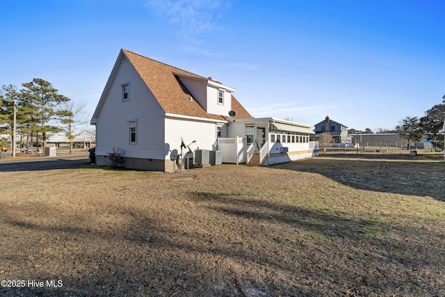 rear view of house with roof with shingles, a yard, and central AC