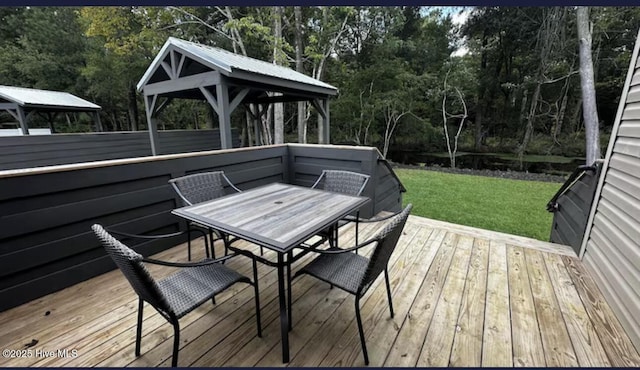 wooden deck featuring outdoor dining area, a yard, and a gazebo