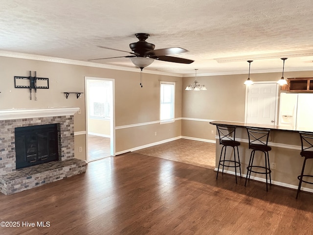 kitchen with a breakfast bar, dark wood-style flooring, crown molding, a textured ceiling, and white fridge with ice dispenser