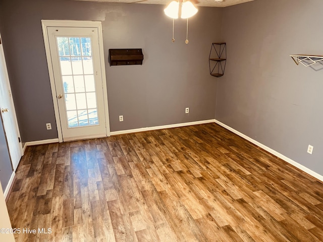 spare room featuring ceiling fan, baseboards, and wood finished floors