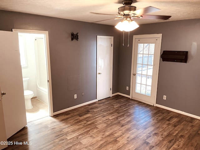 unfurnished bedroom featuring baseboards, connected bathroom, ceiling fan, wood finished floors, and a textured ceiling